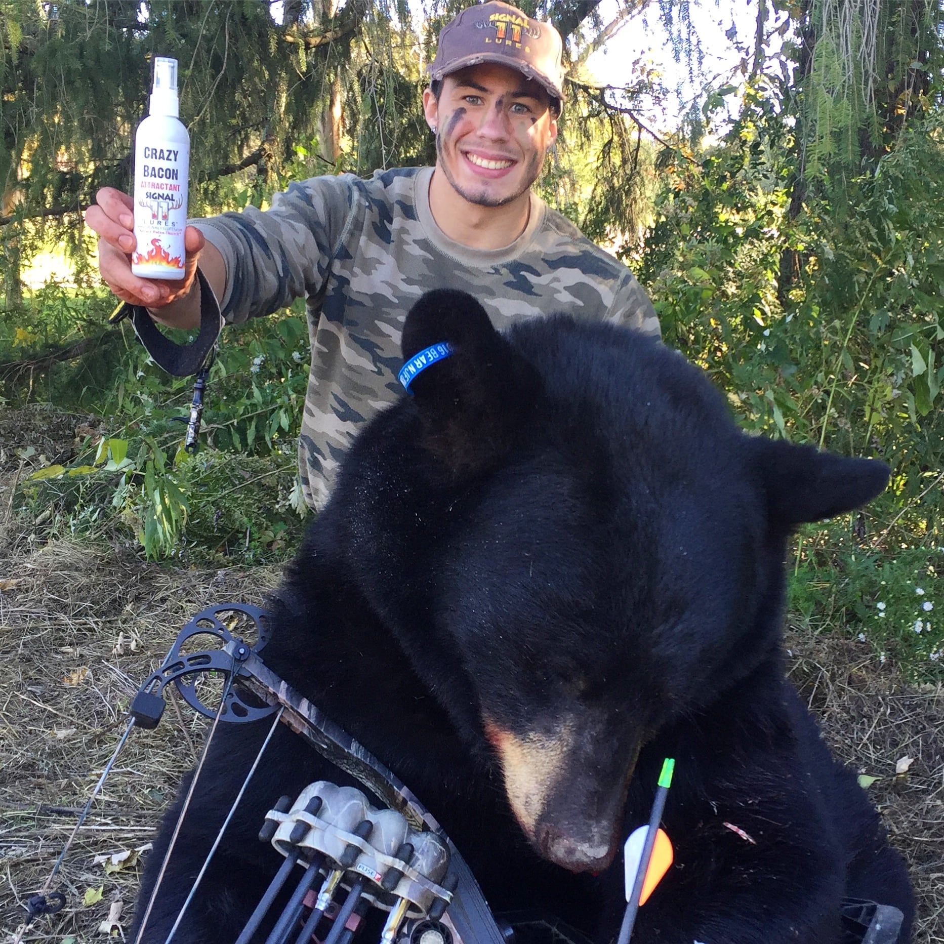 A man holding a bottle of beer next to a bear.
