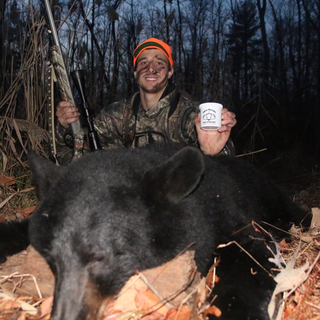 A man holding a cup while standing next to a black bear.
