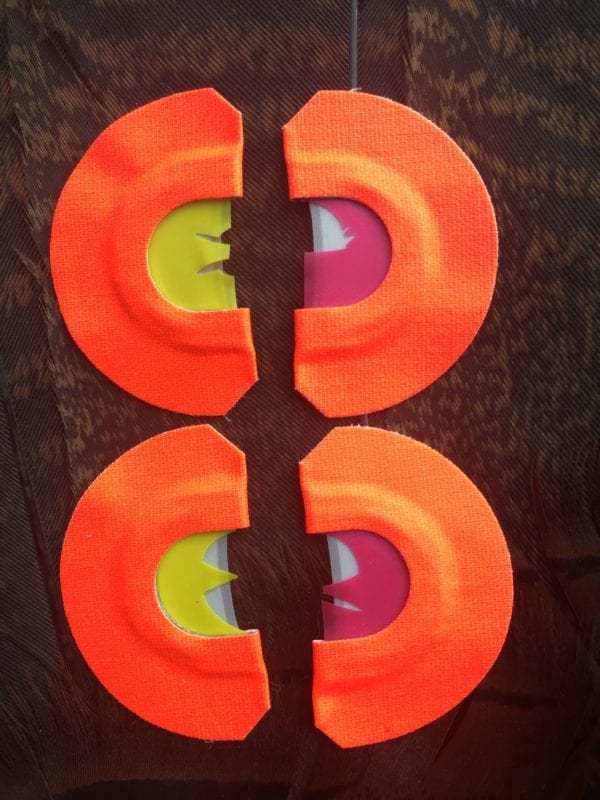 A pair of orange paper plates with a hole in each one.
